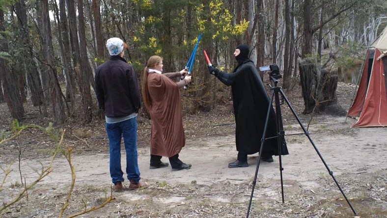 A behind the scenes shot of Kyle and Dean practicing for the lightsaber duel in costume